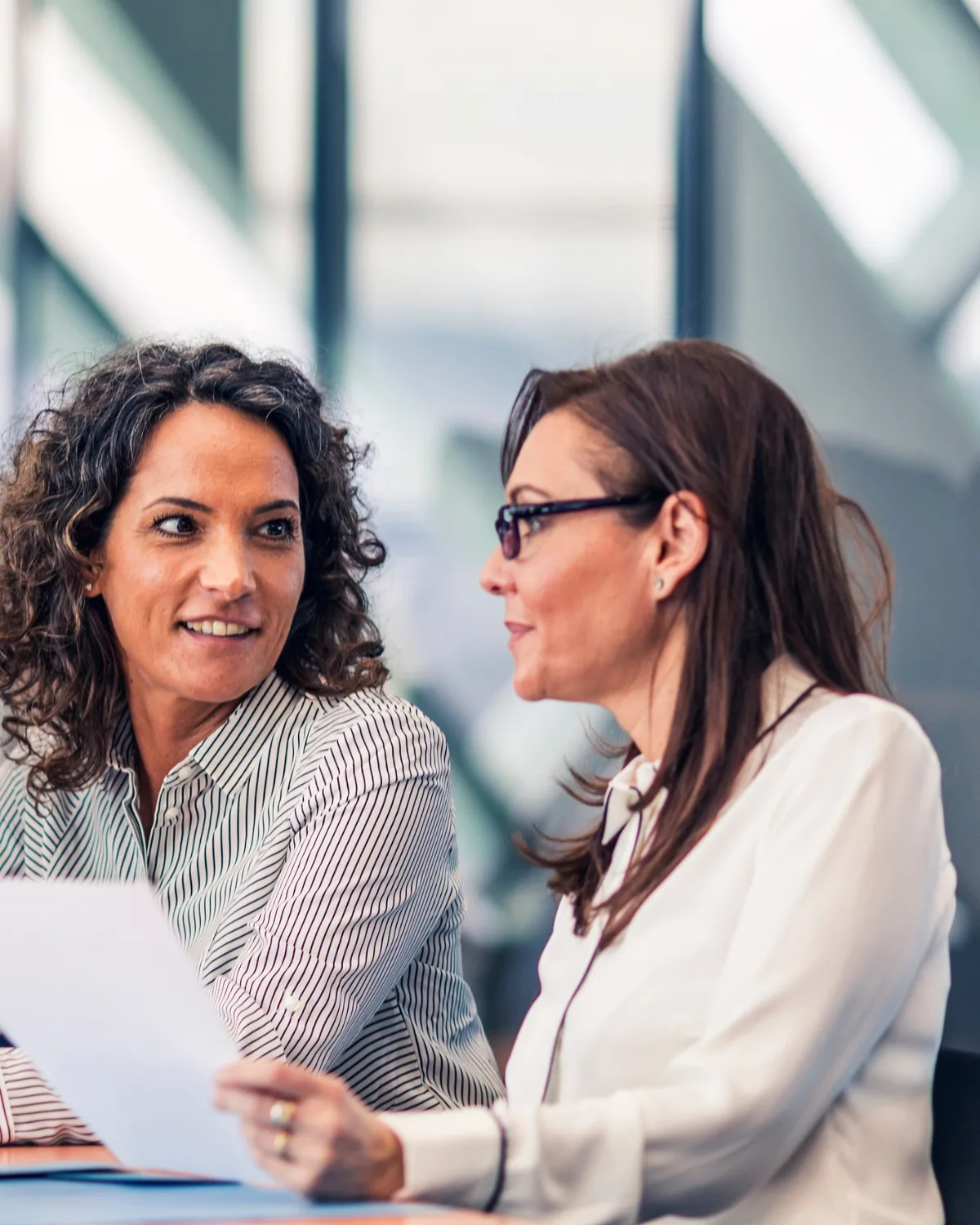 Two women discussing business documents in a bright office